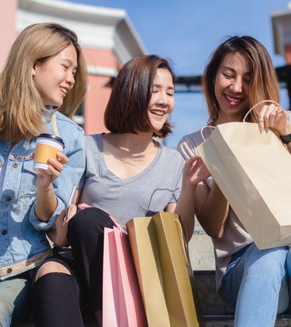 Friends laughing on steps with shopping bags